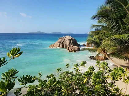 Batu-batu granit dan air berwarna biru kehijauan di sebuah pantai di Seychelles.